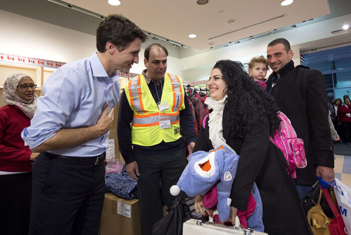 Prime Minister Justin Trudeau, left, greets Georgina Zires, center, Madeleine Jamkossian, second right, and her father Kevork Jamkossian, refugees fleeing from Syria, as they arrive at Pearson International airport on Dec. 11, 2015, in Toronto. Photo: Nathan Denette / The Canadian Press