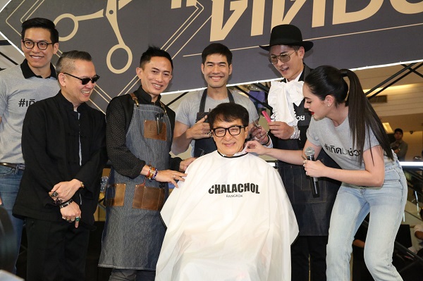Action star and director Jackie Chan gets a haircut Sunday at a Siam Paragon charity event. He donated 2.4 million baht to southern flood relief.