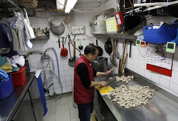 HONG KONG: Chicken feet snacks shop owner Leung Kin-kung chops off chicken feet Monday in Hong Kong. Photo: Vincent Yu / Associated Press