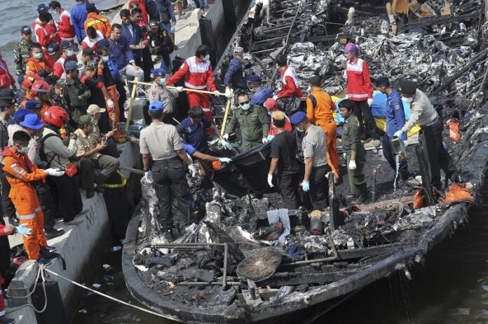 Rescuers search for victims from the wreckage of a ferry that caught fire off the coast of Jakarta after it was docked on Sunday at Muara Angke Port in Jakarta. Photo: Rhana Ananda / Associated Press