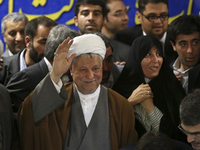 Former President Akbar Hashemi Rafsanjani, waves to journalists in 2013, as he registers his candidacy for the upcoming presidential election, with his daughter Fatemeh, second right, at the interior ministry, in Tehran, Iran. Photo: Ebrahim Noroozi / Associated Press