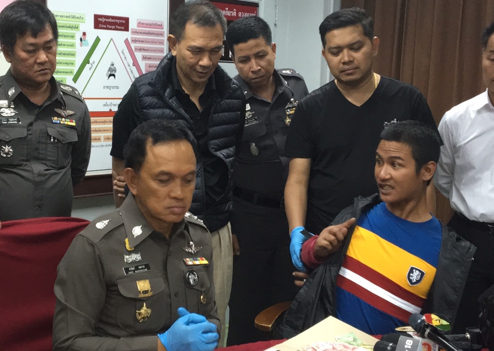 Murder suspect Kittikorn Wikaha, at right, grimaces at Bangkok police commander Sanit Mahatavorn on Friday morning at the Kok Kram Police Station in Bangkok.