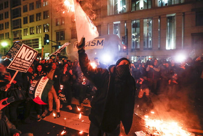 Protesters burn signs outside the National Press Building ahead of the presidential inauguration in Washington D.C. Photo: John Minchillo / Associated Press