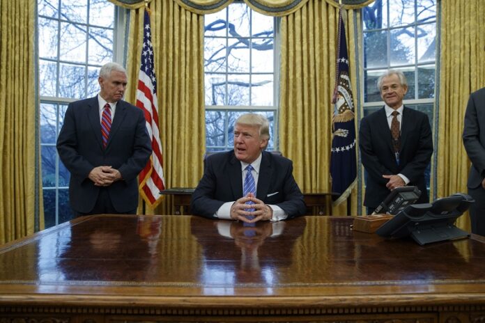 Vice President Mike Pence, left, and National Trade Council adviser Peter Navarro, right, wait for President Donald Trump to sign three executive orders, Monday in the Oval Office of the White House in Washington. Photo: Evan Vucci / Associated Press