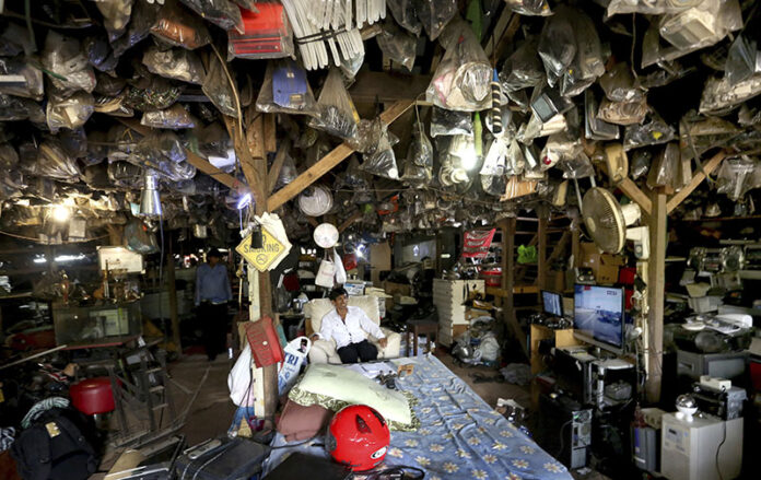 The owner of a used electronic goods stall sits Friday as he waits for customers at his shop in the outskirts of Jakarta, Indonesia. Photo: Tatan Syuflana / Associated Press