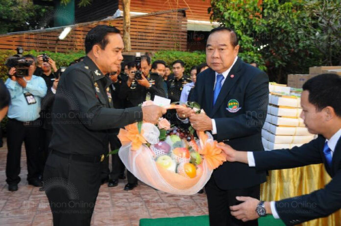 Then-army chief Prayuth Chan-ocha gives a fruit basket as a New Year present to retired army chief Prawit Wongsuwan on Dec. 26, 2013, at his Bangkok residence.