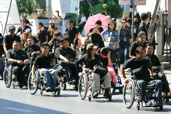Disabled commuters and rights activists rally along Ratchadaphisek Road in Bangkok on their way to the Civil Court on Jan. 20 to file a class-action lawsuit against the city.