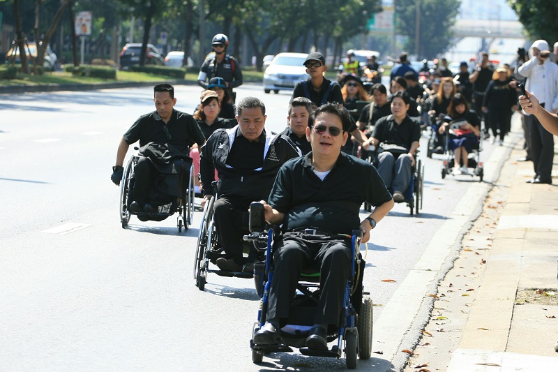 Disabled commuters and rights activists rally along Ratchada Road in Bangkok on their way to the Civil Court on Friday to file a class-action lawsuit against the city.