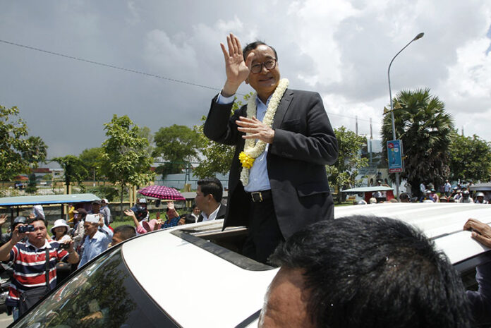 Sam Rainsy, leader of the opposition Cambodia National Rescue Party waves from a car upon his arrival Aug.16, 2015, at Phnom Penh International Airport. Photo: Heng Sinith / Associated Press