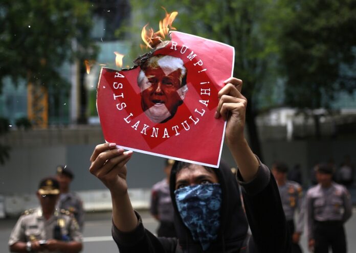 An activist burns a poster depicting U.S. President Donald Trump during a protest Saturday outside the U.S. Embassy in Jakarta, Indonesia. Photo: Dita Alangkara / Associated Press