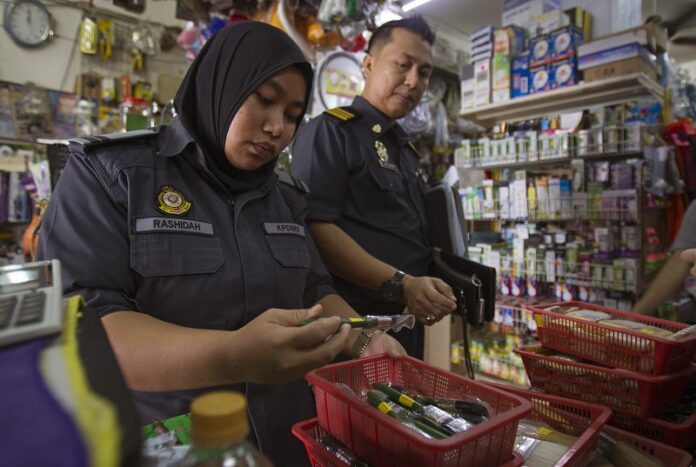 Domestic trade enforcement officers check on the paint brushes that are believed to be made from pig bristles at a hardware store outside, Wednesday in Kuala Lumpur, Malaysia. Photo: Daniel Chan / Associated Press