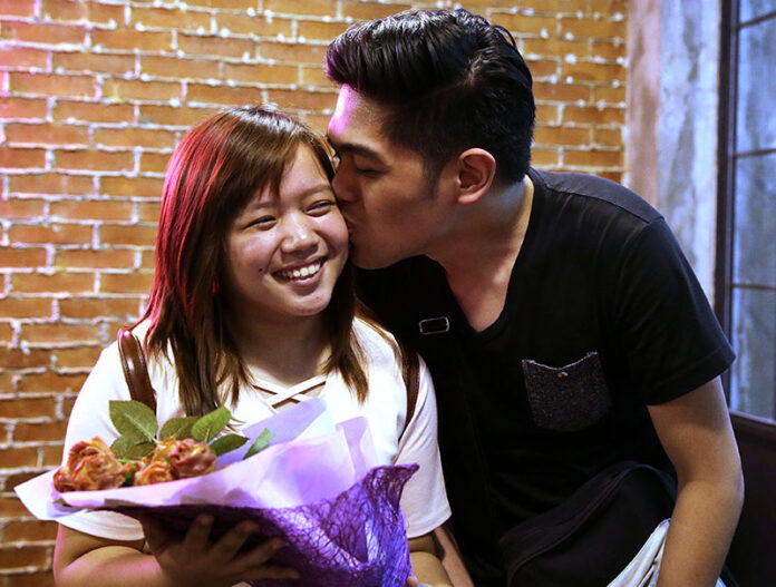 Mica Alcantara, left, smiles as she is kissed by her boyfriend Richmond Ulap after receiving a bouquet of edible rose shaped bacon Friday in Manila. Photo: Aaron Favila / Associated Press