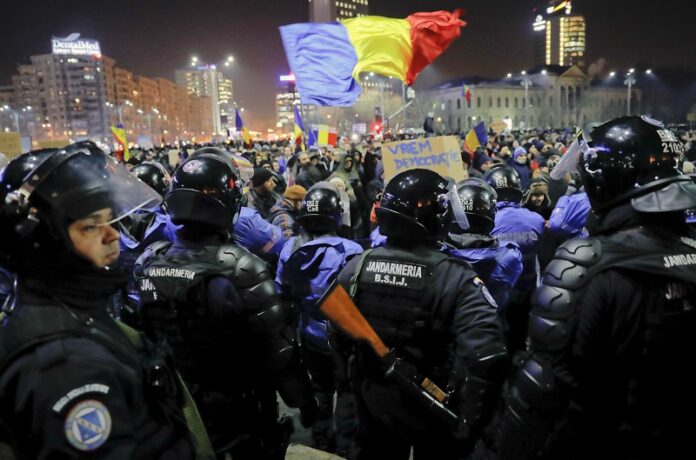 Romanian riot police protect the government building from crowds before minor clashes erupted during a protest Wednesday in Bucharest, Romania. Photo: Vadim Ghirda / Associated Press