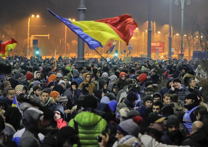 Crowds wave Romanian flags Wednesday outside the government headquarters, during a protest in Bucharest, Romania. Photo: Vadim Ghirda / Associated Press