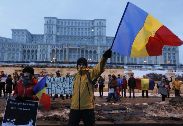 Demonstrator waves Romanian national flag during a protest Saturday in Bucharest, Romania. Photo: Darko Bandic / Associated Press