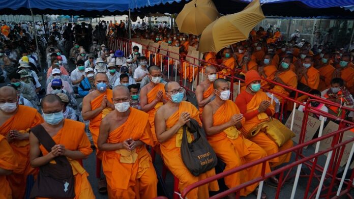 Buddhist monks of the Dhammakaya sect sit anticipating a police raid outside the Dhammakaya sect temple Sunday in Pathum Thani. Photo: Dake Kan / Associated Press