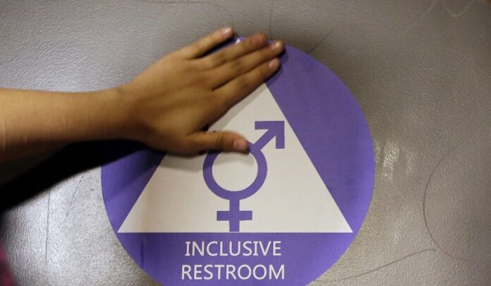 A new sticker is placed on the door at the ceremonial opening of a gender neutral bathroom last May at Nathan Hale High School in Seattle. Photo: Elaine Thompson / Associated Press