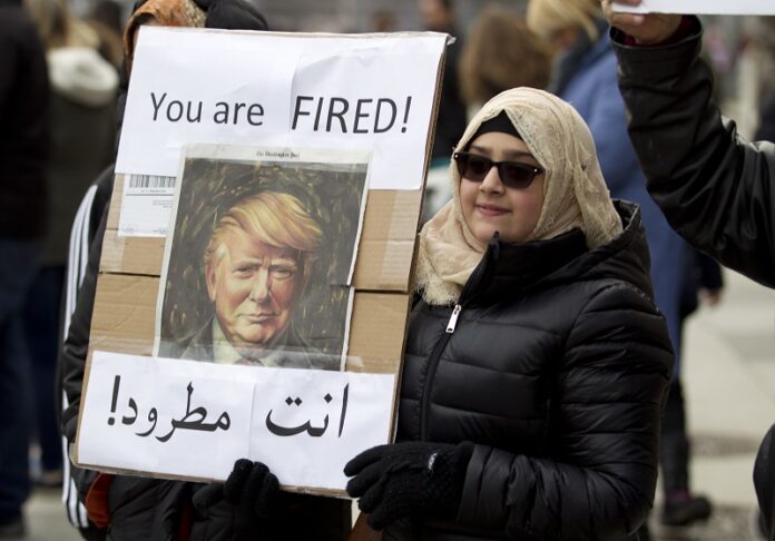 A woman carries a sign outside of the White House during a demonstration to denounce President Donald Trump's executive order that bars citizens of seven predominantly Muslim-majority countries from entering the United States on Sunday in Washington. Photo: Jose Luis Magana / Associated Press