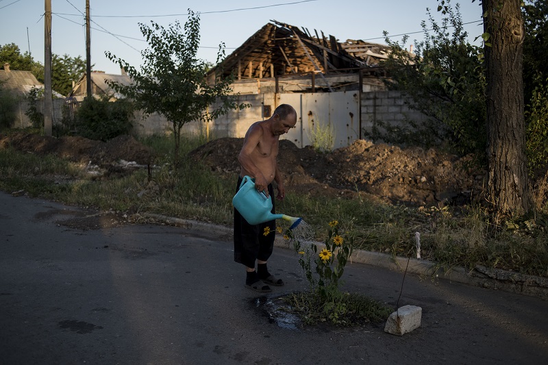 "Black Days Of Ukraine" by photographer Valery Melnikov for Rossia Segodnya, which won first prize in the Long-Term Projects category of the World Press Photo contest shows a man watering flowers on a street in the destroyed village of Spartak, Ukraine. Photo: Valery Melnikov / Associated Press