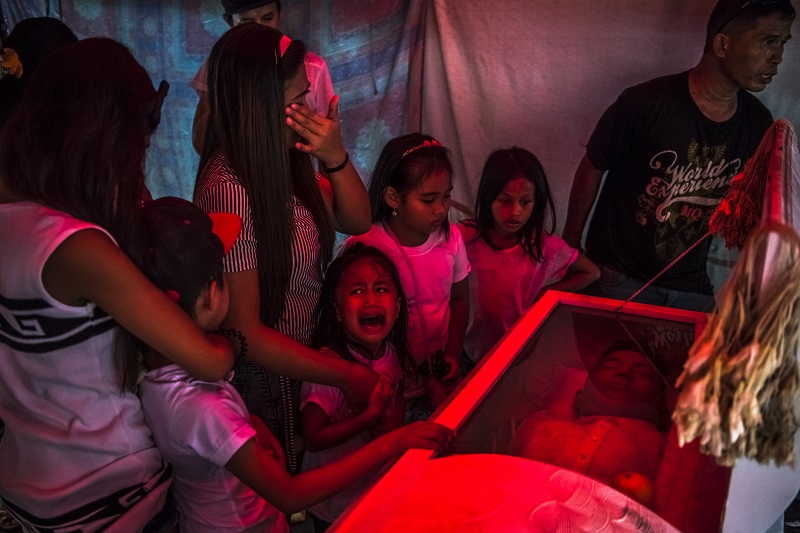 "They Are Slaughtering Us Like Animals" by photographer Daniel Berehulak for The New York Times, which won first prize in the General News, Stories, category of the World Press Photo contest shows six-year-old Jimji crying in anguish as she screams "papa" before funeral parlor workers move the body of her father, Jimboy Bolasa, from the wake at the start of the funeral to Navotas Cemetery in Manila, Philippines. Photo: Daniel Berehulak / Associated Press
