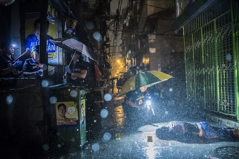 "They Are Slaughtering Us Like Animals" by photographer Daniel Berehulak for The New York Times, which won first prize in the General News, Stories, category of the World Press Photo contest shows heavy rain pouring as police operatives investigate inside an alley where a victim, Romeo Joel Torres Fontanilla, 37, was killed by two unidentified gunmen riding motorcycles in the early morning in Manila, Philippines. Photo: Daniel Berehulak / Associated Press