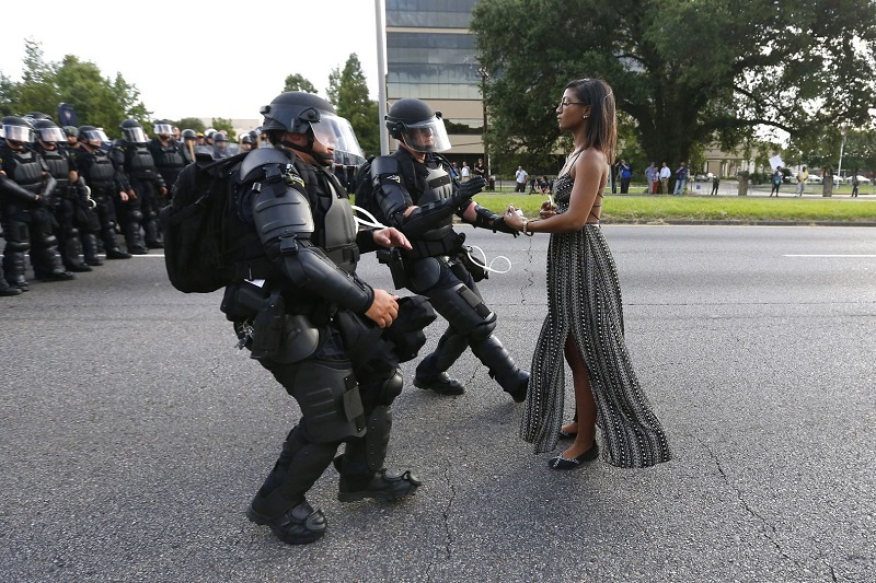 "Taking A Stand In Baton Rouge" by photographer Jonathan Bachman for Thomson Reuters which won first prize in the Contemporary Issues, Singles, category of the World Press Photo contest shows lone activist, Leshia Evans, standing her ground while offering her hands for arrest as she is charged by riot police during a protest against police brutality outside the Baton Rouge Police Department in Louisiana, U.S.A. Photo: Jonathan Bachman / Associated Press