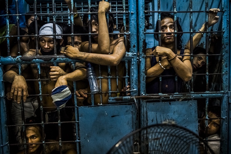 "They Are Slaughtering Us Like Animals" by photographer Daniel Berehulak for The New York Times, which won first prize in the General News, Stories, category of the World Press Photo contest shows inmates watching as drug suspects are processed inside a police station in Manila, Philippines. Photo: Daniel Berehulak / Associated Press