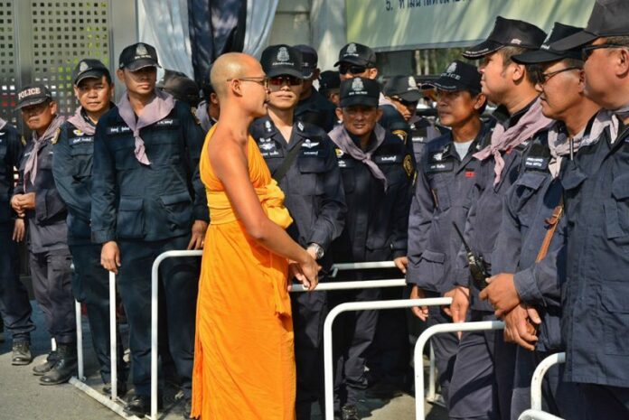 Monk talks to police outside Wat Dhammakaya on Thursday.