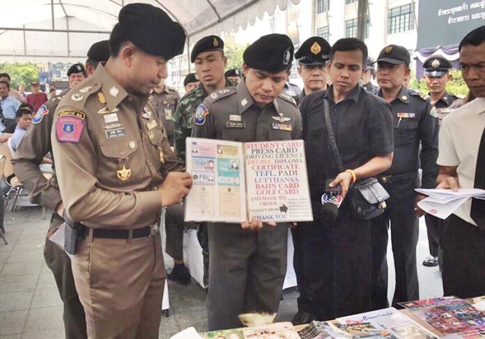 Police peruse the professional and academic certifications advertised by a forgery suspect Tuesday afternoon in Bangkok’s Phra Nakhon district.