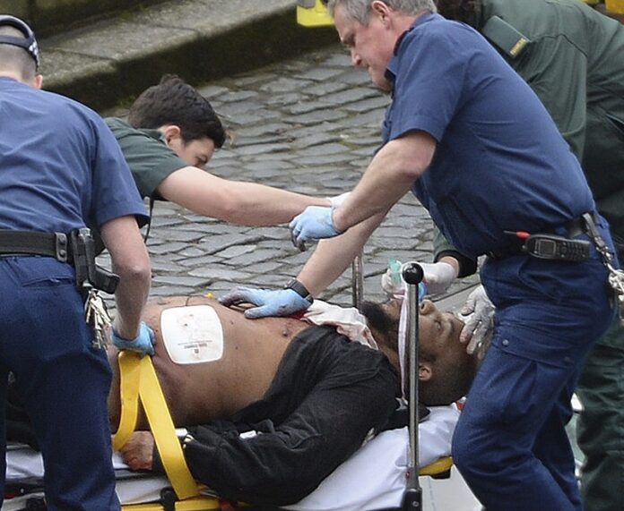 An attacker is treated by emergency services Wednesday outside the Houses of Parliament London. Photo: Stefan Rousseau / Associated Press