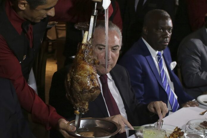 Brazil's President Michel Temer, center, alongside Angola's Ambassador to Brazil, Nelson Manuel Cosme, attend a steak dinner Sunday at a traditional Brazilian barbecue restaurant after a meeting on the rotten meat scandal in Brasilia, Brazil. Photo: Eraldo Peres / Associated Press