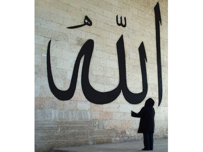 Woman looking at large writing of the word Allah in Arabic script in 1999 in Edirne old Mosque, Turkey. Photo: Nevit Dilmen / Wikimedia Commons