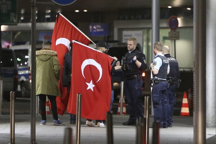 People with Turkish flags are watched by police as they gather to protest the cancellations of events with Turkish politicians in the Netherlands on Sunday at the airport in Duesseldorf, Germany. Photo: David Young / Associated Press