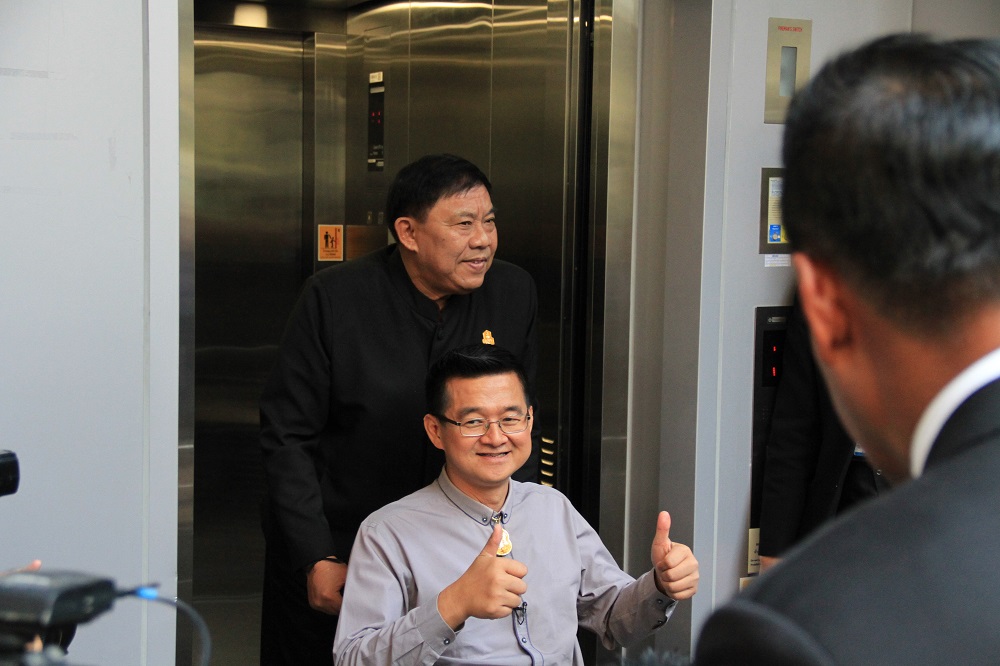 Bangkok Gov. Aswin Kwanmuang gestures as reporter Krisana Lalai exits an elevator at BTS Ratchadamri in a wheelchair Friday in Bangkok.