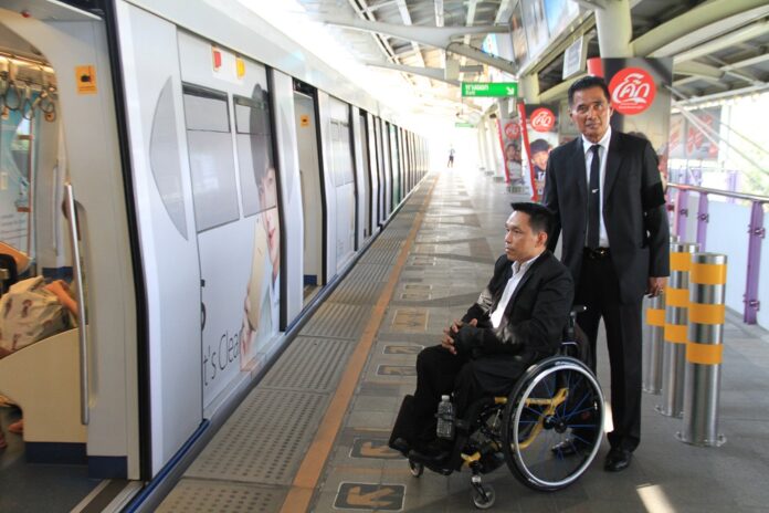 Deputy Bangkok Gov. Amnuay Nimmano assists disabled right activist Manit Inpim to the platform of BTS Ratchadamri on March 3.