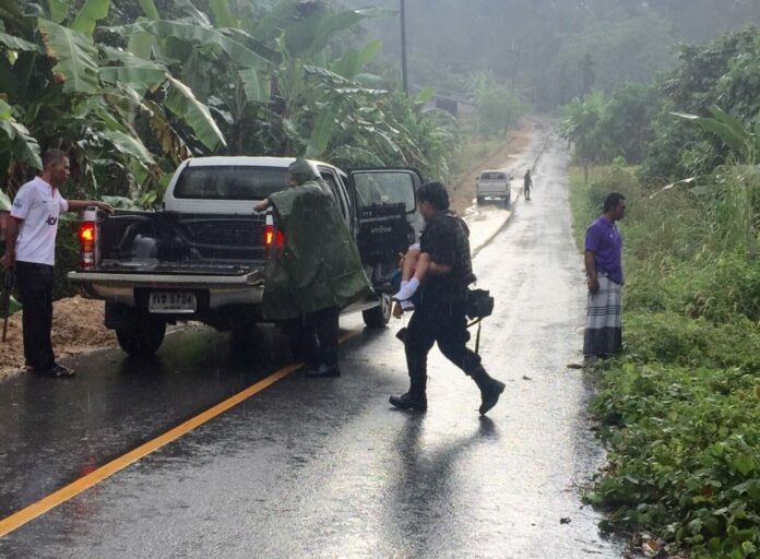 A security officer carries the body of an 8-year-old student killed Thursday along with three members of his family in the Rueso district of Narathiwat province. Two other children were injured.