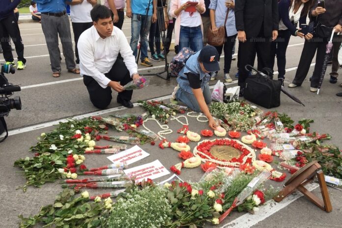 A pro-democracy activist on June 24, 2016, lays down flowers about the 1932 revolution plaque at the Royal Plaza in Bangkok