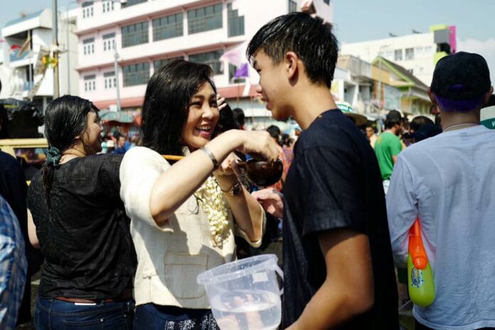 Yingluck Shinawatra and son Supasek Amornchat splashing water at each other Friday on Tha Phae Road, Chiang Mai province. Photo: Yingluck Shinawatra / Facebook.
