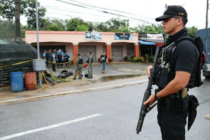 A police officer stands guard while investigators comb a checkpoint in Yala province for evidence of an April 3 grenade attack.