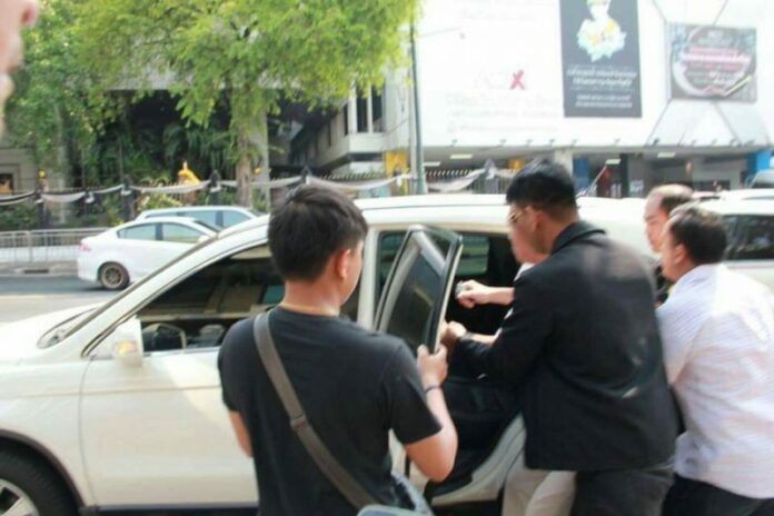 Ekachai Hongkanwan seen here Tuesday morning as he is taken into a nondescript vehicle in front of Government House. Photo: Piyarat Chongthep / Facebook