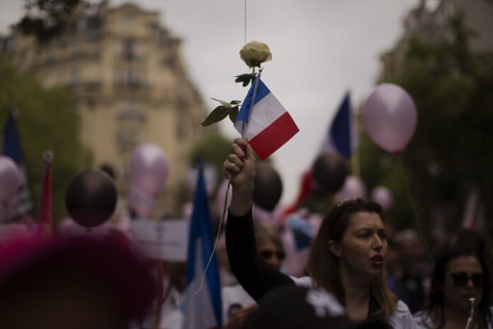 A woman holds a rose and a French flag during a demonstration in what was described as a march of support for all French security forces Saturday in Paris. Photo: Emilio Morenatti / Associated Press