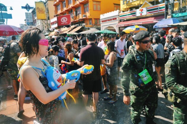 A woman with a Doraemon water gun backpack sprays soldiers during 2017 Songkran celebrations on Khaosan Road.