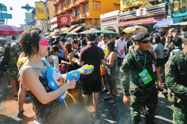 A woman with a Doraemon water gun backpack sprays soldiers during 2017 Songkran celebrations on Khaosan Road.