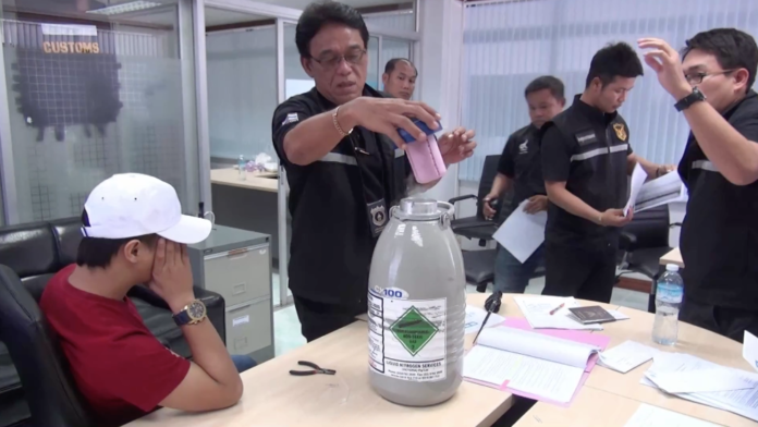 Nithinon Srithaniyanant, at far left, covers his face as customs officers examine his nitrogen-cooled tank of semen Thursday in Nong Khai province.