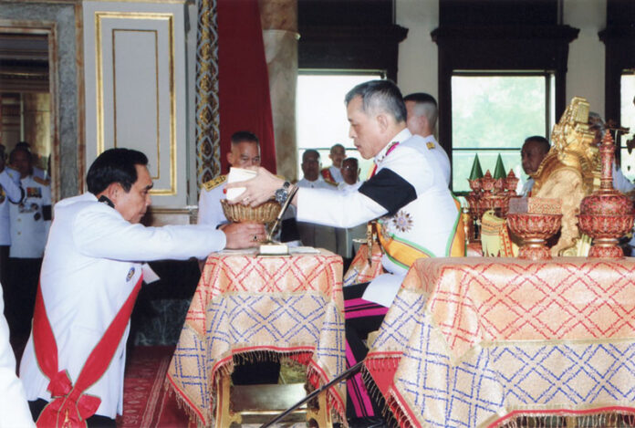 King Vajiralongkorn presents the new constitution to junta leader and Prime Minister Prayuth Chan-ocha on Thursday in Bangkok.