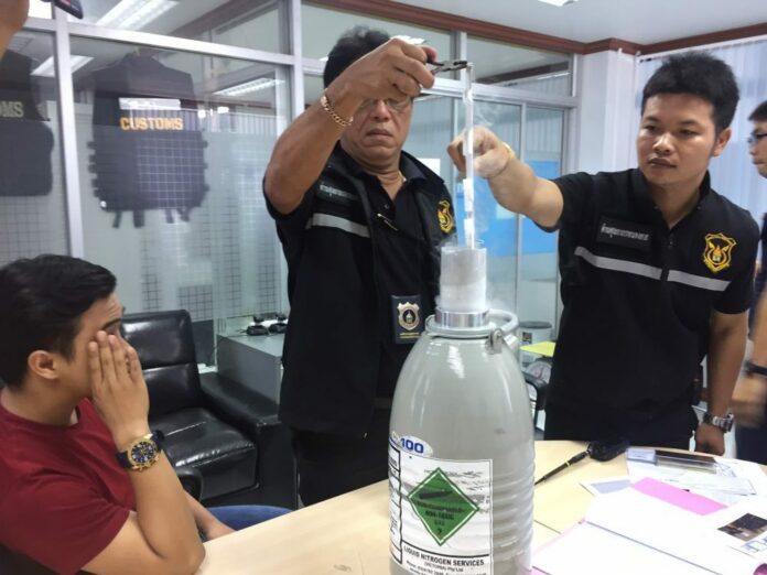 Nithinon Srithaniyanant, at far left, covers his face as customs officers examine his nitrogen-cooled tank of semen Thursday in Nong Khai province.