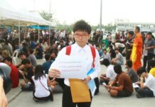 Junta Files Complaints Against 41 More Protesters With a sign decrying the draft as "outdated and unnecessary," activist Netiwit Chotiphatphaisal defers enlistment for one year in 2017.