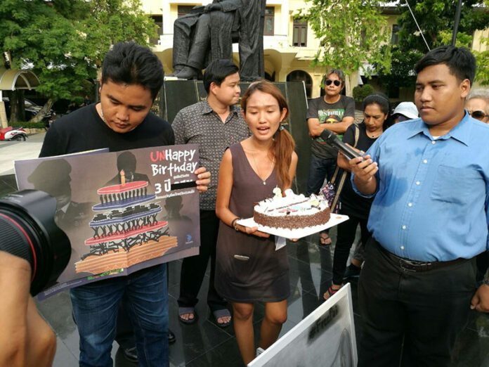 Chonticha Jangrew of the Democracy Restoration Group, holding cake, with Sirawith 'Ja New' Seritiwat, at right, and other pro-democracy activists mark the third anniversary of the 2014 coup on Monday at Thammasat University's Tha Pra Chan campus.