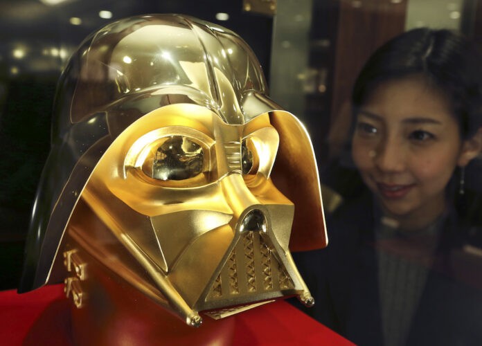 Tokyo gold jeweler Ginza Tanaka employee Momoko Marutani looks at the gold mask of Darth Vader at the jewelry shop in Tokyo, Monday. Photo: Koji Sasahara / AP.