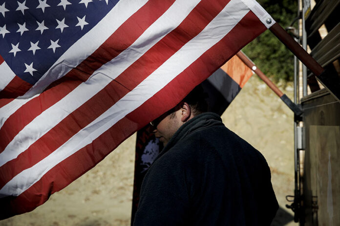 Iraq war veteran Colt Romberger pauses behind an American flag hanging from his trailer in 2017 in Santa Clarita, California. Photo: Jae C. Hong / Associated Press Iraq war veteran Colt Romberger pauses behind an American flag hanging from his trailer in 2017 in Santa Clarita, California. Photo: Jae C. Hong / Associated Press